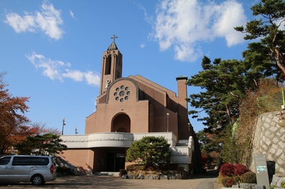 1999년 철근 콘크리트 구조에 붉은 벽돌 마감으로 신축된 새 성당 외부.