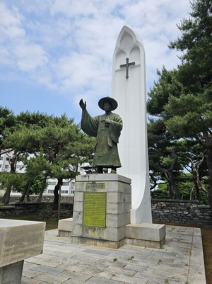 성 김대건 안드레아 신부상과 성인을 감싸고 있는 성모상 형상의 기념탑.